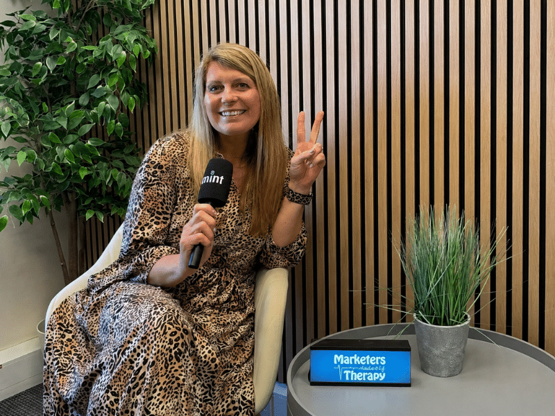 Emma smiling, holding microphone, peace sign.